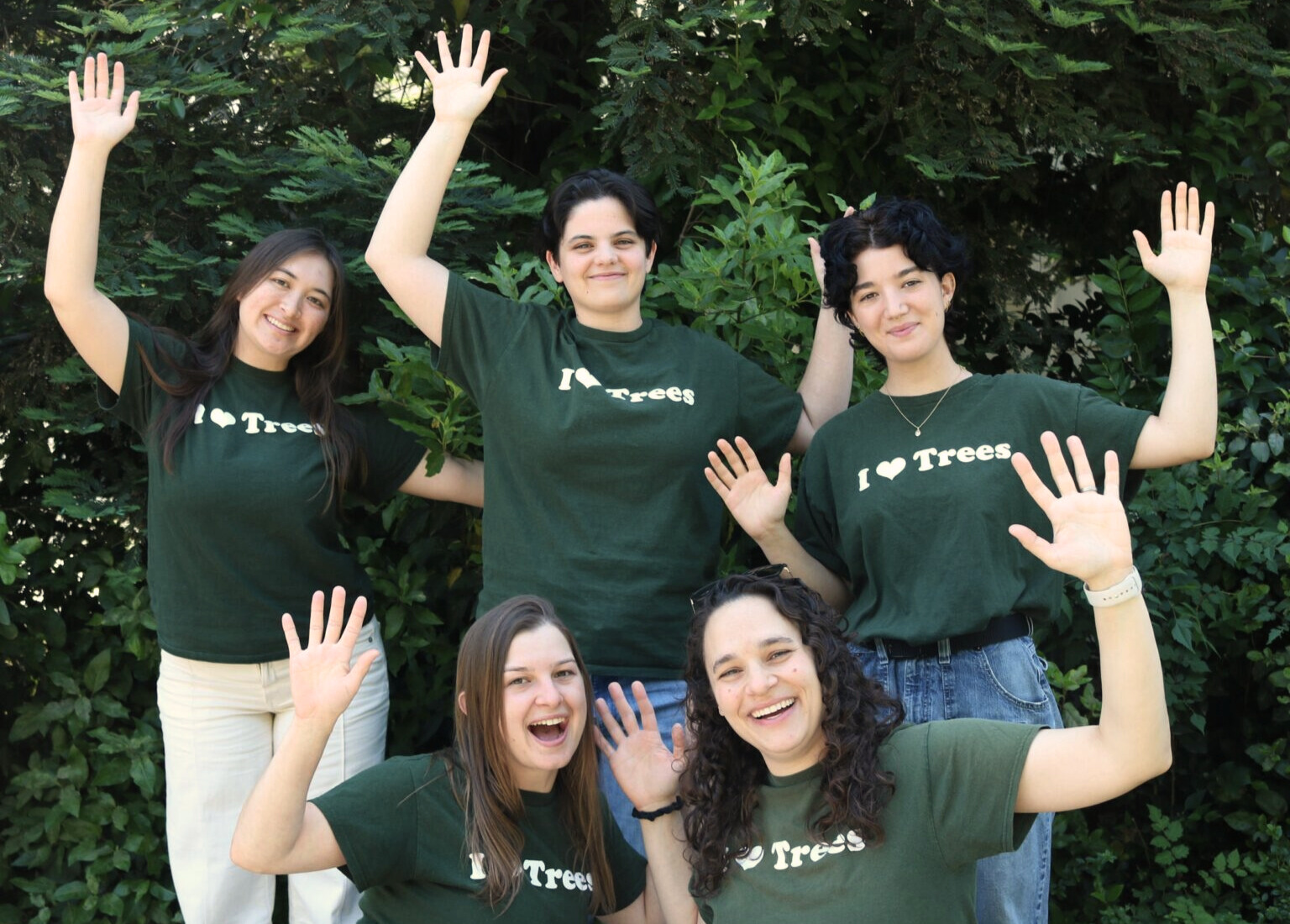 Staff members hold hands up and smile.