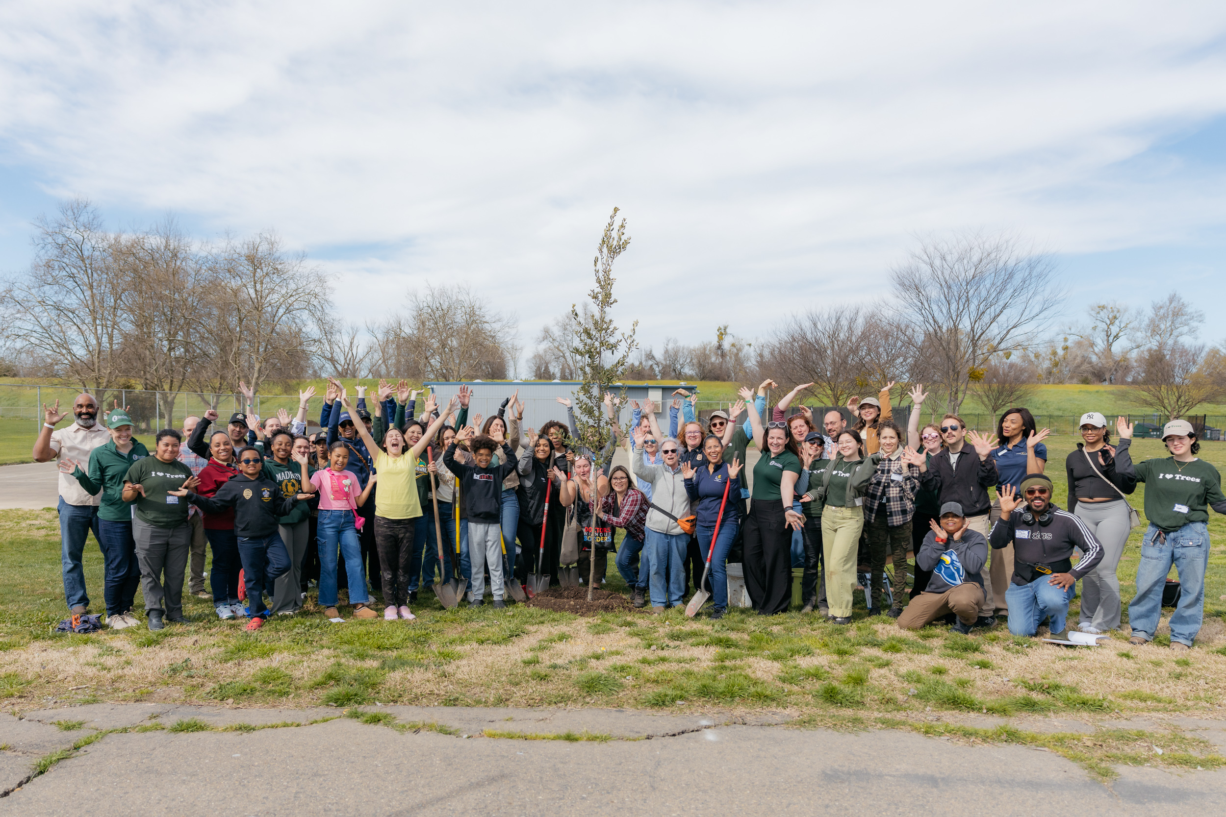 Volunteers smile and post with a newly planted tree at Tree Davis event.
