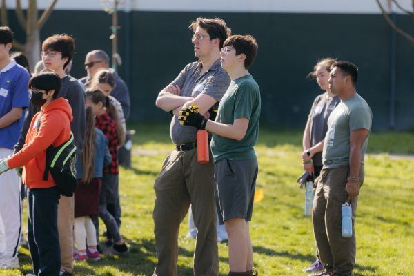 Volunteers stand and listen at a planting event.