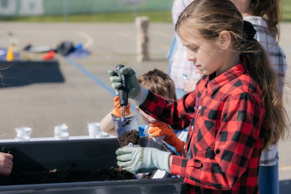 Child collects soil in a small bucket.