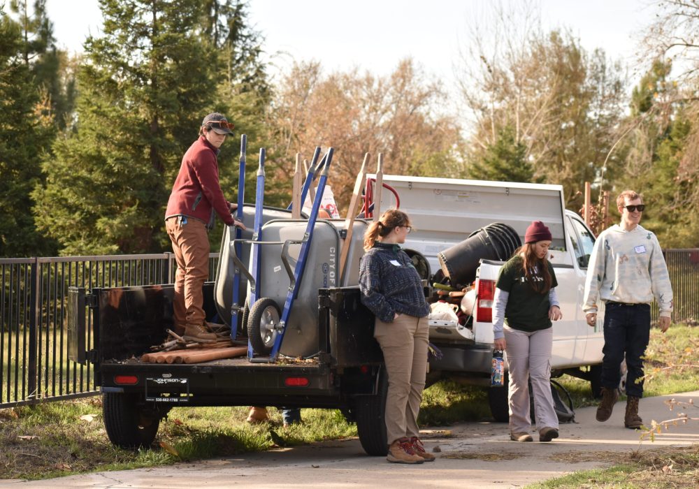Staff stands and loads tools into truck trailer.
