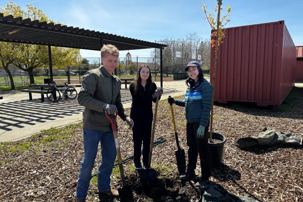 Students pose with planting tools at a park.